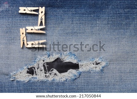 Blue denim jeans with the clothespin made from wood in the scene present the old denim look and old damaging fabric that shown detail of texture background and wording 2 from clothespin.