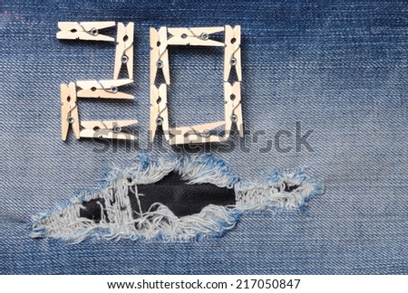 Blue denim jeans with the clothespin made from wood in the scene present the old denim look and old damaging fabric that shown detail of texture background and wording 20 from clothespin.