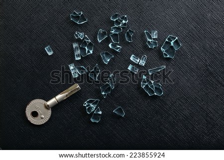 A broken door key put among broken tempered glass represent the material damaged abstract meaning