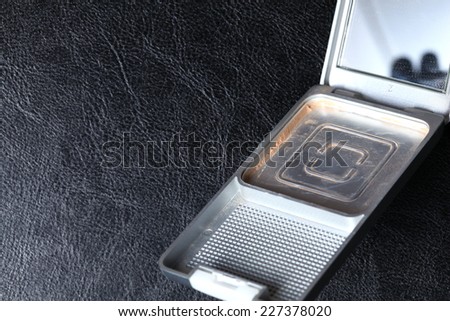Beauty face power containing case with mirror lid with empty powder inside represent the value of product using .