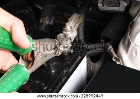 Man hand in action of doing jump start technique with car battery by using jump start cable in the scene focus to the cable forceps