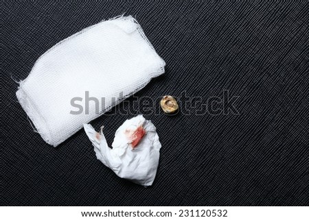 Crown teeth on black leather background put beside gauze and tissue with blood stain represent the oral healthcare and dental equipment.