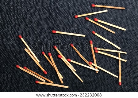 Matchsticks put on the black color leather surface as a background represent the flammable material.