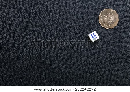 Hongkong dollar coin and dice put on the black color leather surface as a background represent the finance and gambling.