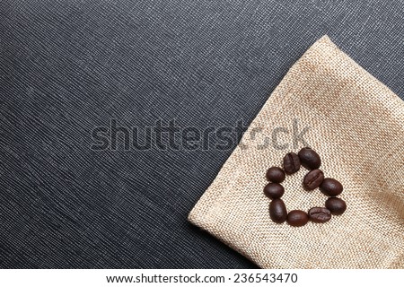 Coffee bean arrange to the shape of heart put on the coffee bean sack in the scene appear the back color leather background