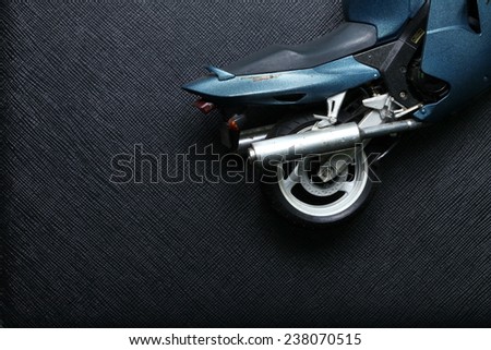Old and dirty motorcycle plastic model in action of lie down put on black color leather background represent the accidental abstract meaning.