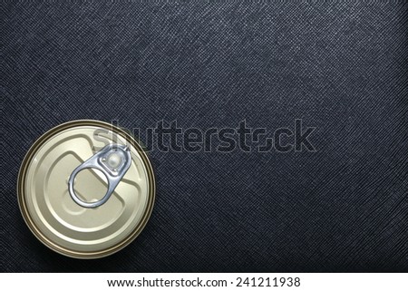 Closed canned food put on black color leather surface background represent the food containing material.
