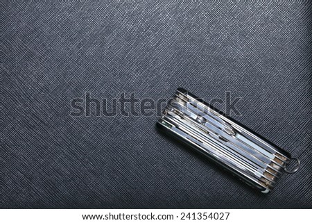 Old and classic stainless steel utility knife set put on black color leather surface background represent the knife equipment.
