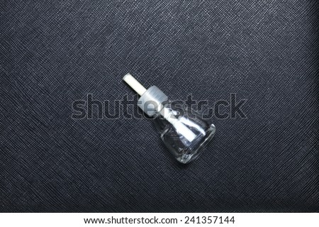 Old and empty car perfume bottle put on black color leather surface background represent the car deodorant related.