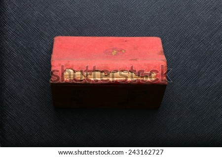 The old dirty and vintage small diary  with damaged with fabric covering pale red color put on the black color leather background represent the vintage style of diary.