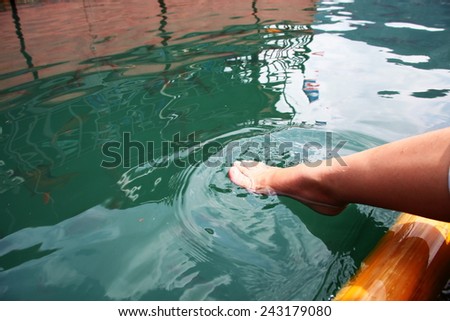 Foot dipping into the fresh water in lake among daytime natural light represent the relaxation activity.