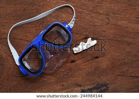 Diving mask goggles and coral put on the hard  wood brown color surface background represent the skin diving equipment