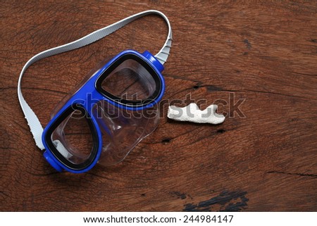 Diving mask goggles and coral put on the hard  wood brown color surface background represent the skin diving equipment