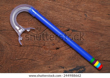 Snorkel tube put on the hard  wood brown color surface background represent the skin diving equipment