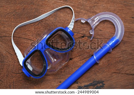 Snorkeling and diving mask goggles put on the hard  wood brown color surface background represent the skin diving equipment