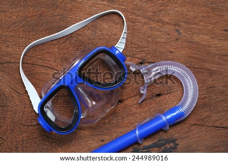 Snorkeling and diving mask goggles put on the hard  wood brown color surface background represent the skin diving equipment