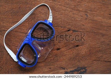 Diving mask goggles put on the hard  wood brown color surface background represent the skin diving equipment