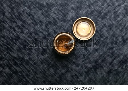A bottle of gold color for plastic model paint with white color plastic stirring rod on the top of bottle put on the black color leather surface background represent the model making material.
