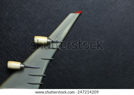 Old plastic airplane model focus at wing and turbine engine part put on the black color leather surface background represent the airplane part.