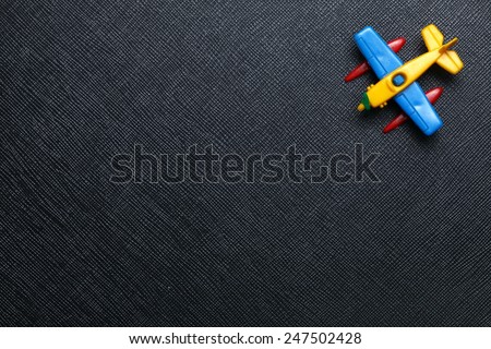 Old plastic airplane toy model with the propeller engine type put on the black color leather surface background represent the airplane and aviation related.