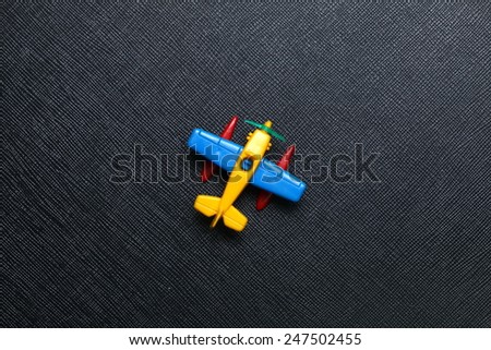 Old plastic airplane toy model with the propeller engine type put on the black color leather surface background represent the airplane and aviation related.