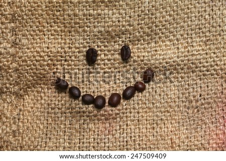 Coffee beans arrange in smiling face put on the coffee bean sack or gunny sack  brown color represent texture surface background.