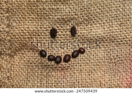 Coffee beans arrange in smiling face put on the coffee bean sack or gunny sack  brown color represent texture surface background.