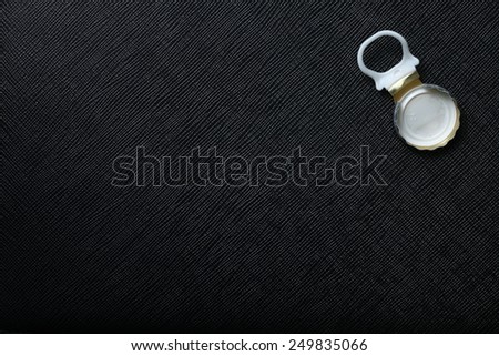 Used water bottle cap pulling type made from aluminum put on the black color leather background represent the beverage containing equipment related