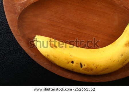 Banana with natural scratch mark on the peel put on the old natural wood plate hole background represent the healthy food and fruit related.