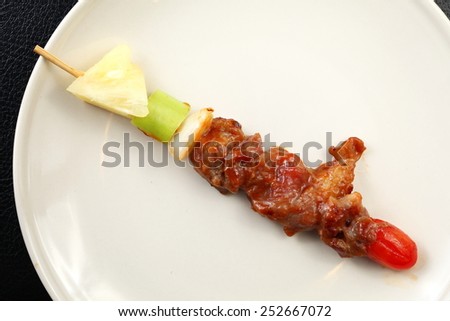 Barbecue beef and chicken ready to serve on the beige color plate put on the black color leather surface background represent the cooked food related.