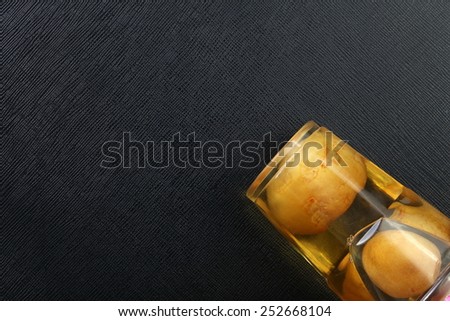Preserved lemon pickle in the food grade plastic containing cup plate put on the black color leather surface background represent the preserved food related.