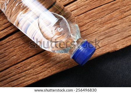 Drinking water bottle with blue color cap made from transparent food grade plastic put on the haed wood background represent the water containing material related.