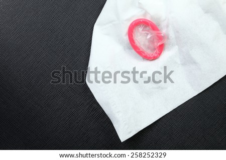 Pink color condom and tissue paper put o put on the black color leather background represent the sex education concept idea related.