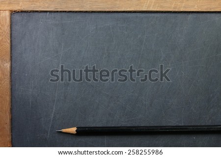 Vintage and old slate blackboard and wooden pencil put on the black color leather background represent the teaching equipment related.