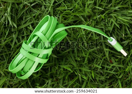 Charger wire green color put on grass background represent the mobile phone device equipment material related.