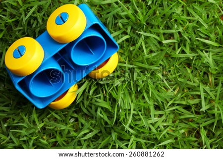 Old brick toy in shape of vehicle with wheel put on the green color grass represent the outdoor toy concept idea related.