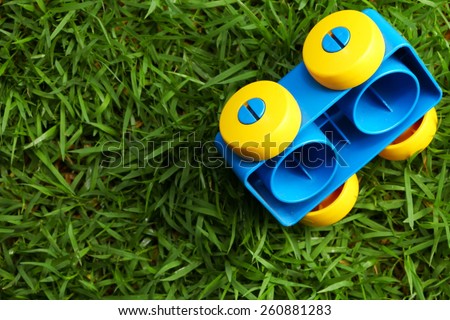 Old brick toy in shape of vehicle with wheel put on the green color grass represent the outdoor toy concept idea related.