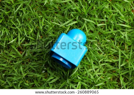 Old brick toy blue color put on the green color grass represent the outdoor toy concept idea related.