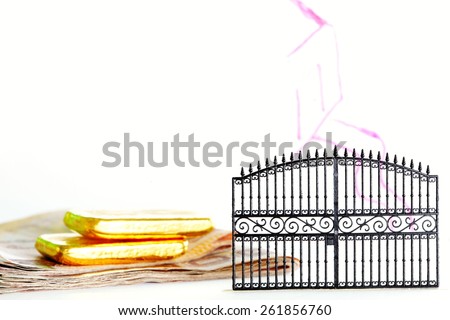 Thailand banknotes and gold bar put beside the plastic gate model in the scene appear the hand drawing house shape on clear acrylic surface represent the mortgage concept idea.