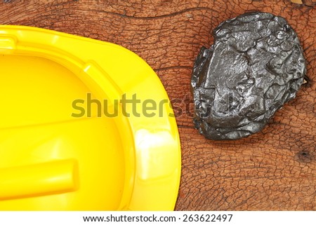 sedimentary rock element beside safety helmet put on the hard wood brown color surface as a background represent the construction material. Super macro shot and intention focus at the rock.