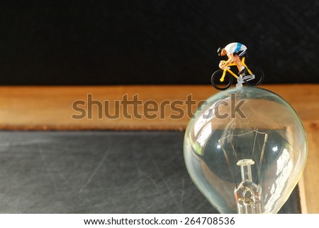Old fashion of tungsten light bulb and figure cycling action model represent the saving energy and cycling activity concept related idea. Super macro shot and intention focus at figure model.
