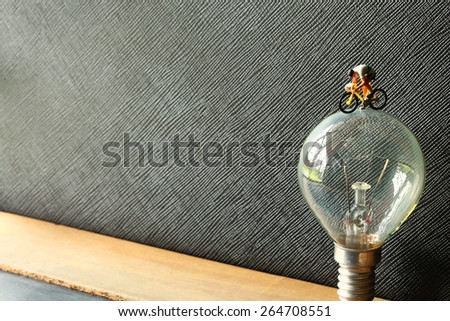 Old fashion of tungsten light bulb and figure cycling action model represent the saving energy and cycling activity concept related idea. Super macro shot and intention focus at figure model.