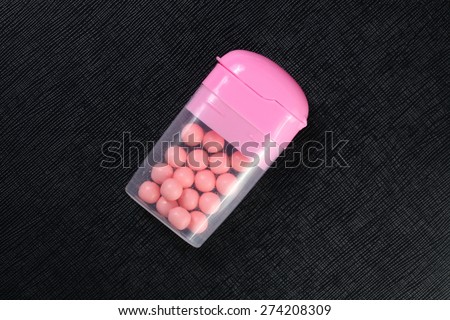 Candy and chewing gum pink color in the clear plastic box represent the confectionery concept related idea.