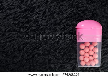 Candy and chewing gum pink color in the clear plastic box represent the confectionery concept related idea.