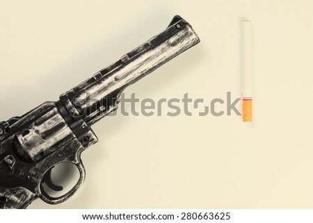 Cigarette and plastic toy gun represent the tobacco concept related idea.