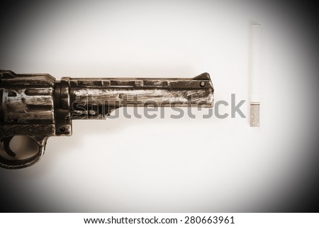 Cigarette and plastic toy gun with old scenic appearance represent the tobacco concept related idea.