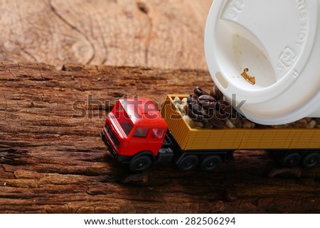 Coffee beans on old hard wood with toy truck model represent coffee business concept related idea . Super macro shot and intention focus at the truck.