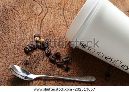 Coffee beans coffee cup and spoon on old hard wood represent coffee business concept related idea . Super macro shot and intention focus at the cup.