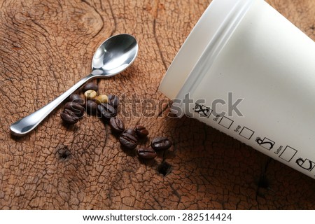 Coffee beans coffee cup and spoon on old hard wood represent coffee business concept related idea . Super macro shot and intention focus at the cup.