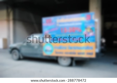 Blurry photo of light weight truck carry advertising board at the rear of car represent the media advertising concept related idea.